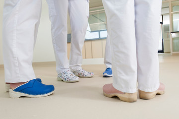 Low section of group of nurses wearing surgical scrubs and clogs