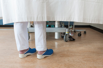 Feet of nurse behind hospital room privacy curtain