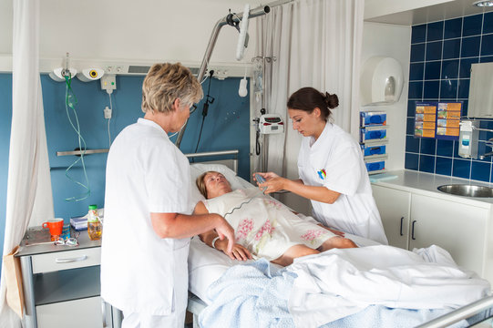 Nurses tending to patient in hospital bed