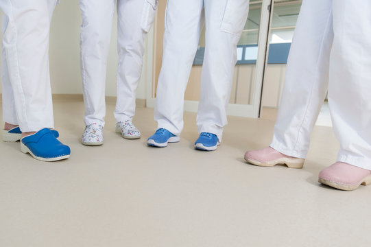 Low section of group of nurses wearing surgical scrubs and clogs