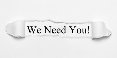 We Need You! on white torn paper