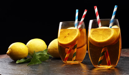 Iced tea with lemon slices, mint and ice on rustic background