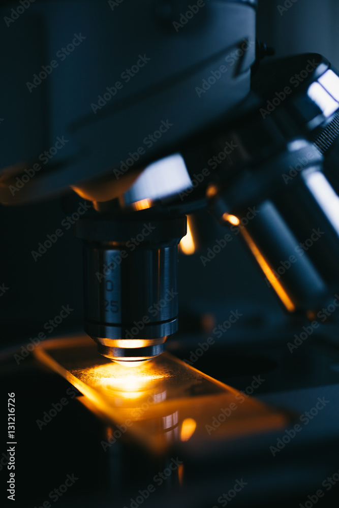 Wall mural close up of examining of test sample under the microscope in laboratory.