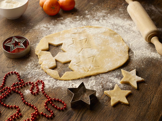 Table with christmas star biscuit dough and rolling pin