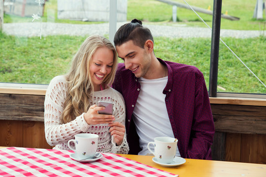 Young couple looking at smartphone update in cafe