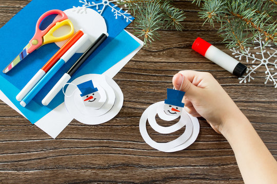 Child sticks details toy on the Christmas tree snowman paper. Gl