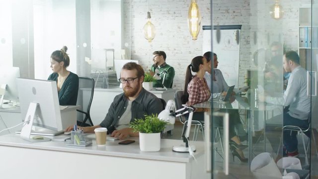 Weekday in a Busy Creative Bureau. Office People Working at Their Personal Computers, Talking on the Phone. Man Joins Coworkers at Conference Table .Shot on RED EPIC (uhd).