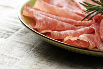 Slices of salami sausage on wooden table. Selective focus
