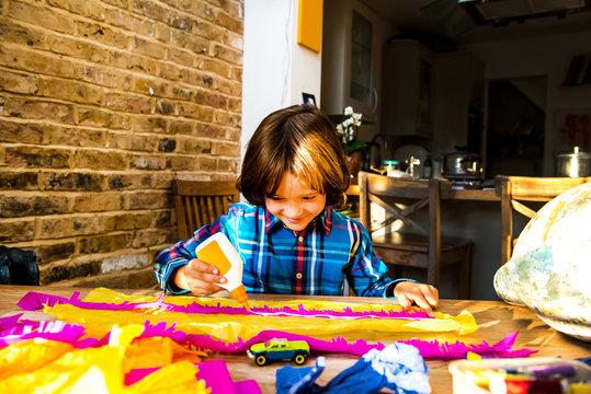 Boy spreading glue on crepe paper to make pinata