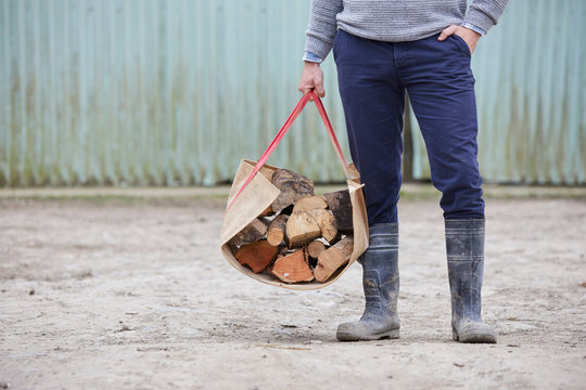 Waist down of man holding logs in log carrier