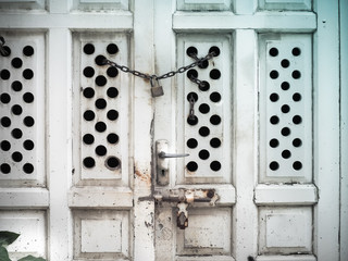 Padlock and iron chain on an old white door