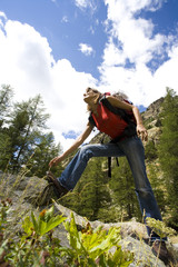 Naklejka premium femme souriant avec un sac à dos qui grimpe dans la montagne