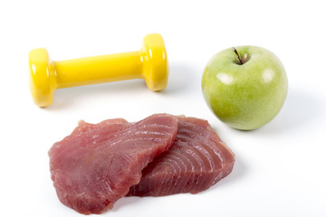 Fresh big raw fillet steak slices of Tuna with dumbbells and green apple on white background for gourmet or vegetarian. Healthy low fat full of omega 3 acid dinner for people on diet after workout.