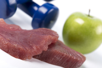 Fresh big raw fillet steak slices of Tuna with dumbbells and green apple on white background for gourmet or vegetarian. Healthy low fat full of omega 3 acid dinner for people on diet after workout.