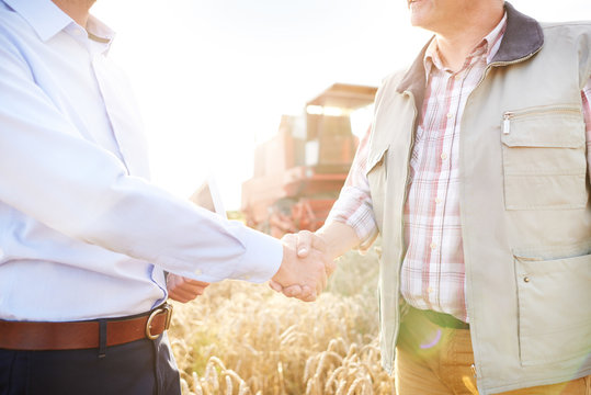 Cropped view of farmer and businessman in wheat field shaking hands