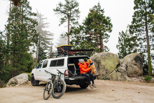 Woman and dog sitting on tailgate of jeep wagon, Sequoia National Park, California, USA