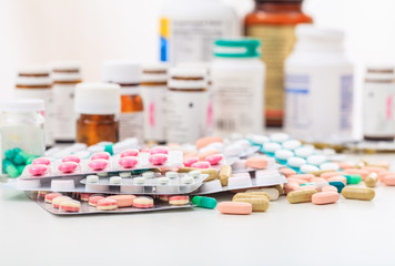 Stack of pills and containers on white background