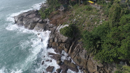 Aerial top view of sea waves hitting rocks on the beach in Phuket, Thailand