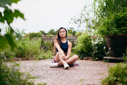 Portrait of beautiful young woman sitting on paving stones of abandoned house, Victoria Peak, Hong Kong