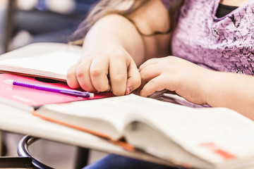 Close up of teenage girl's hands at desk in high school lesson