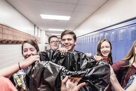 Teenage high school students carrying bin in school locker room