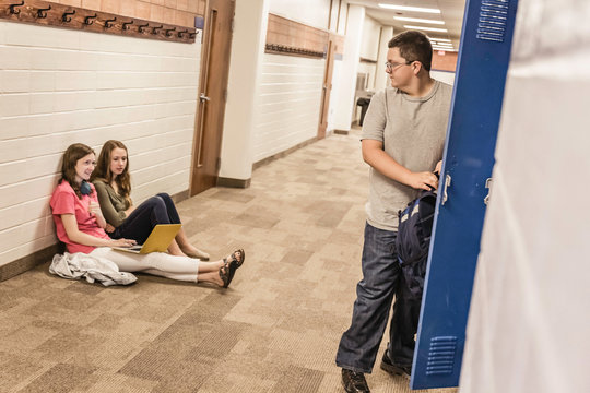 Boy looking over his shoulder at teenage girls in high school locker room