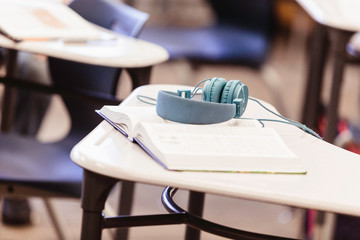 Text book and headphones on high school classroom desk