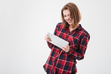 Fototapeta premium Smiling girl in plaid shirt playing games with tablet computer