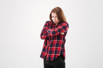 Pretty offended girl in plaid shirt standing with hands crossed