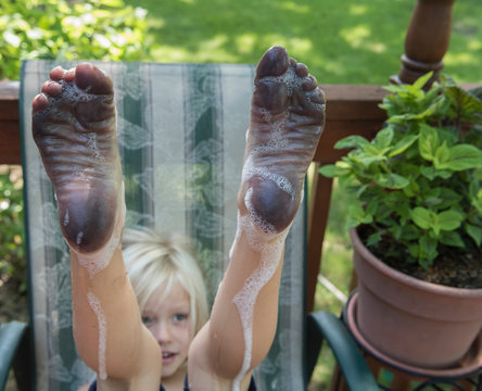 Boy with dirty wet soapy bare feet raised