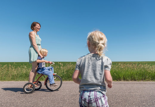 Mother and children riding tricycle in rural area