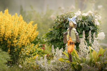Garden scarecrow in the garden among the flowers