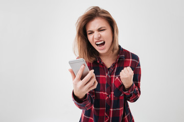 Fototapeta premium Young woman in plaid shirt shouting at mobile phone