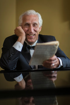 Portrait of senior man at piano holding sheet music
