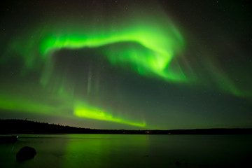 Northern Lights in Starry Sky - Bright northern lights rolling over the starry night sky over a lake. Yellowknife, NWT, Canada.
