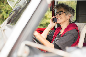 Elderly female car mechanic making a phone call