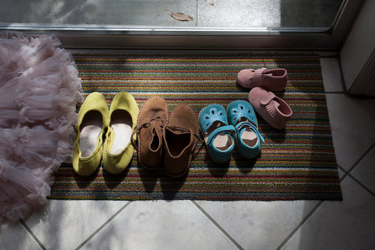 Different Size Shoes Lined Up On Doormat