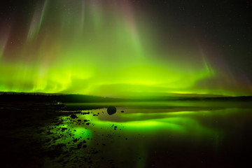 Rolling Lights - Layers of bright rolling northern lights reflecting in a rocky lake.
