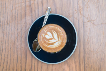 coffee cup with heart shape latte art on wood table 
