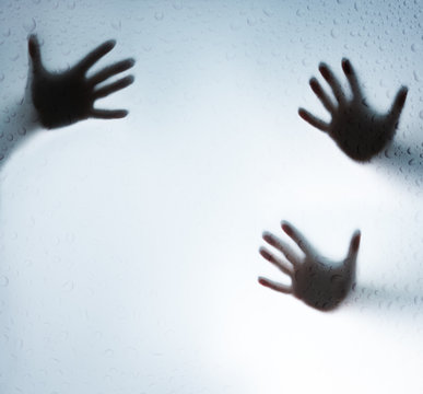 Silhouette Of A Hand Behind The Wet Glass