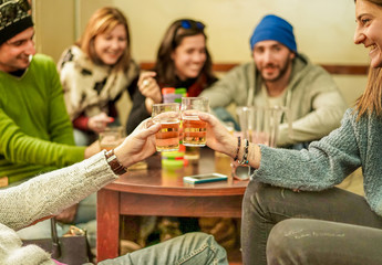 Group of happy friends cheering with beer after skiing day in bar