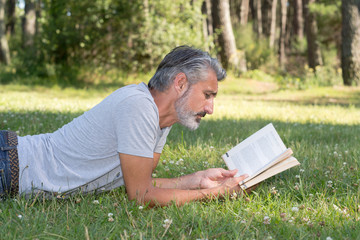 man lyingsitting in the grass reading a book