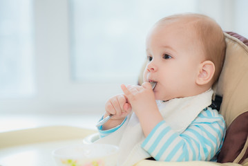 baby holding a spoon in his mouth