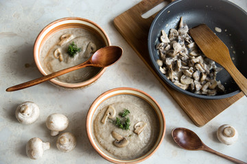 Cream of mushroom soup for lunch for two. wooden spoon and frying pan with mushrooms