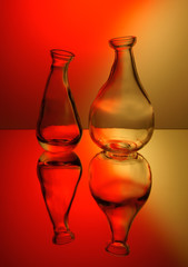 Two colorless transparent decorative bottle in red and yellow rear light through the matte screen.