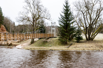 Naklejka premium Diminishing perspective of wooden suspension footbridge over riv
