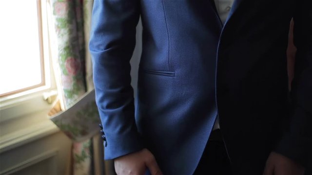 Buttoning a jacket hands close up. Stylish no face man in suit fastens buttons and straightens his jacket preparing to go out. Nervous fingers get ready before date or meeting fashion style weight fit