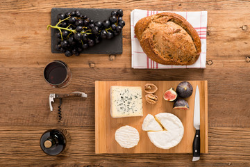above overhead view flat lay assortment of various cheese with traditional bread fruits glass and bottle of red wine on old wooden table