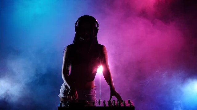 Girl sexy DJ with headphones playing on turntables. Slow motion