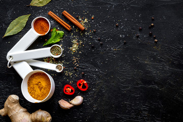 spices in wooden spoons on dark background top view